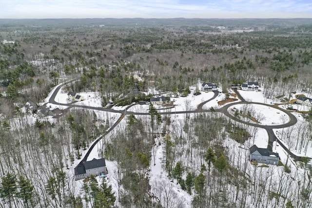 snowy aerial view featuring a wooded view