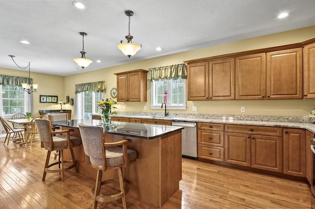 kitchen featuring brown cabinetry, light wood-type flooring, a kitchen island, and stainless steel dishwasher