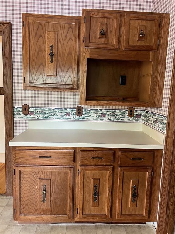 318 Holden St, Holden, MA 01520 - kitchen with wallpapered walls, brown cabinetry, and light countertops