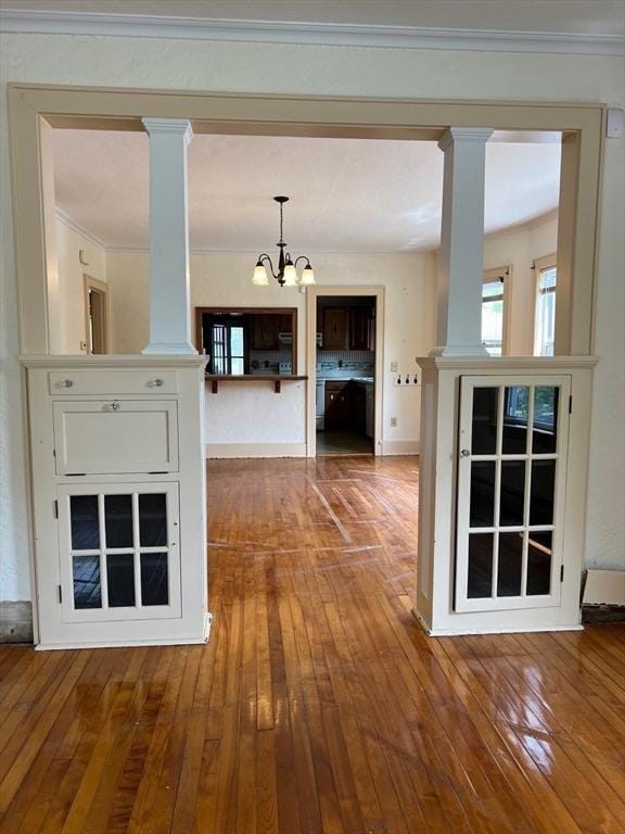 318 Holden St, Holden, MA 01520 - unfurnished living room with decorative columns, a chandelier, hardwood / wood-style floors, ornamental molding, and baseboards