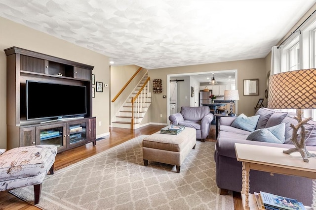67 Hillside St, Rowley, MA 01969 - living area with wood finished floors, stairway, baseboards, and a textured ceiling