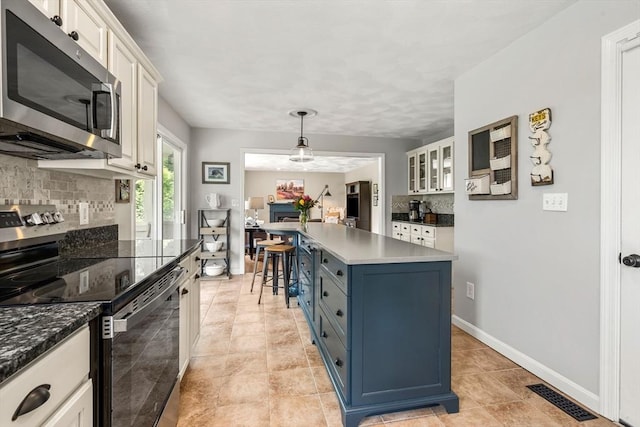 67 Hillside St, Rowley, MA 01969 - kitchen with appliances with stainless steel finishes, decorative backsplash, a breakfast bar area, blue cabinets, and a kitchen island