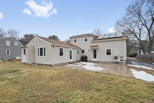 back of house featuring a lawn, solar panels, and a patio