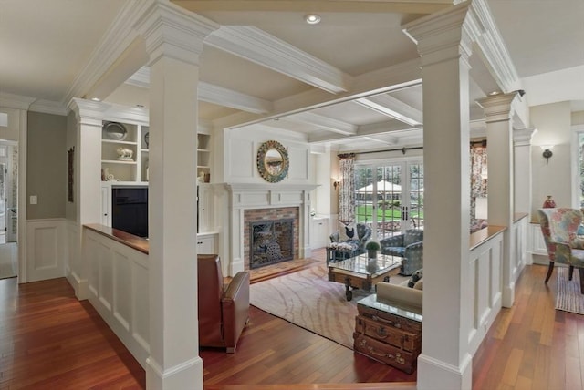 living area featuring crown molding, ornate columns, hardwood / wood-style floors, and a decorative wall