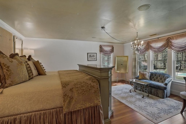 bedroom featuring visible vents, wood finished floors, baseboards, a notable chandelier, and ornamental molding