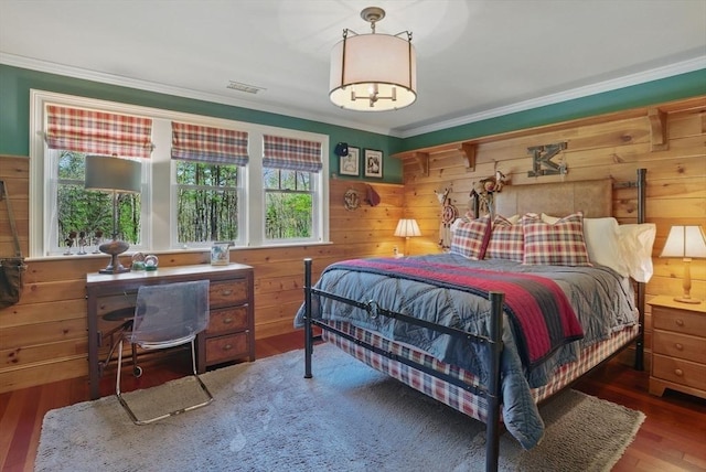 bedroom featuring wooden walls, multiple windows, ornamental molding, and wood finished floors