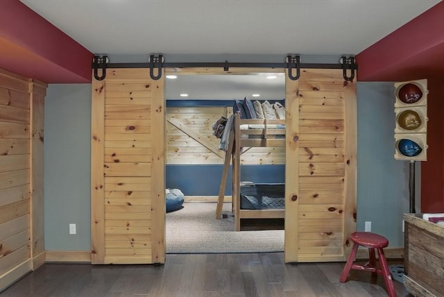 interior space with baseboards, a barn door, and wood finished floors