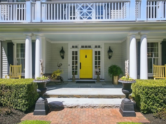 view of exterior entry with a porch and a balcony