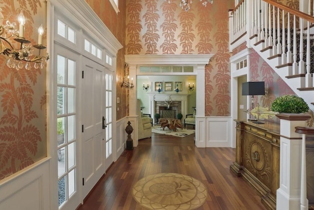 entrance foyer featuring a wainscoted wall, a decorative wall, dark wood-style flooring, and a towering ceiling
