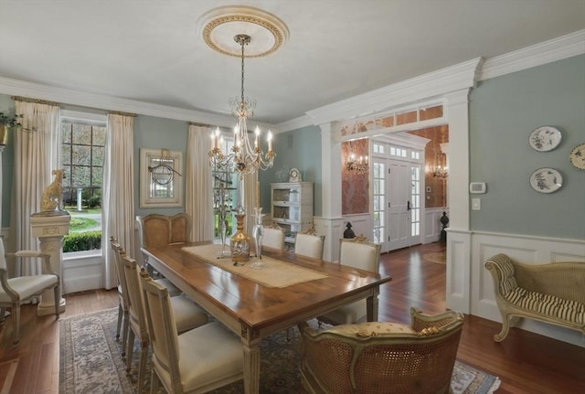 dining area featuring wood finished floors, ornamental molding, a decorative wall, and a notable chandelier
