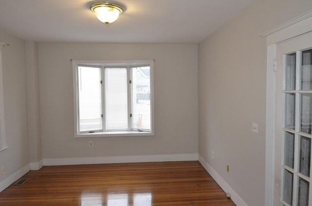 unfurnished room with baseboards, visible vents, and wood finished floors