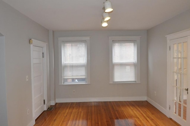 unfurnished room featuring baseboards, plenty of natural light, visible vents, and light wood finished floors