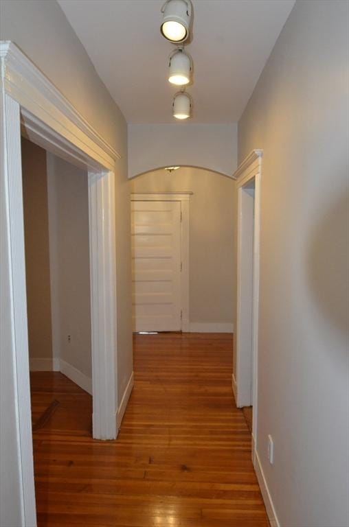 corridor featuring baseboards and wood finished floors