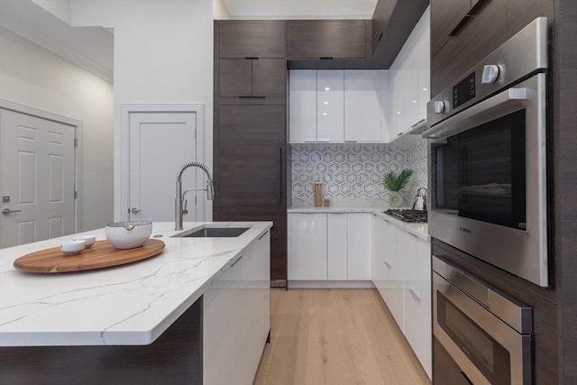 kitchen with white cabinets, stainless steel appliances, light stone countertops, and sink