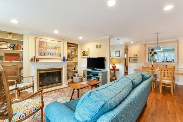 living room featuring crown molding, sink, built in features, and light hardwood / wood-style floors