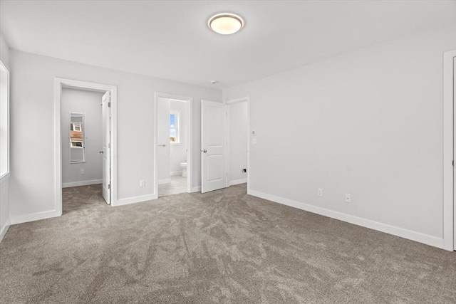 unfurnished bedroom with carpet floors, baseboards, and ensuite bathroom