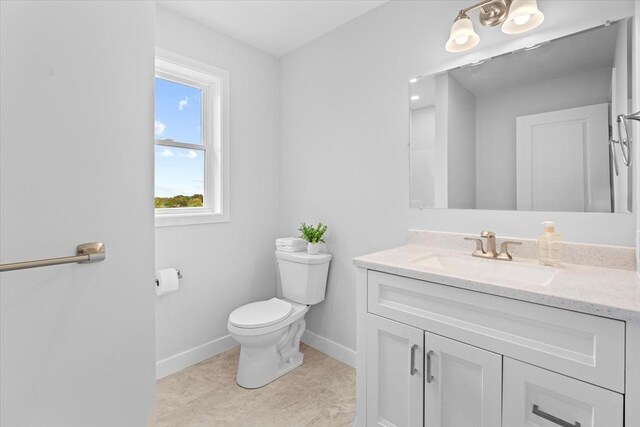 bathroom with toilet, baseboards, and vanity