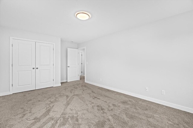 unfurnished bedroom with carpet, baseboards, and a closet