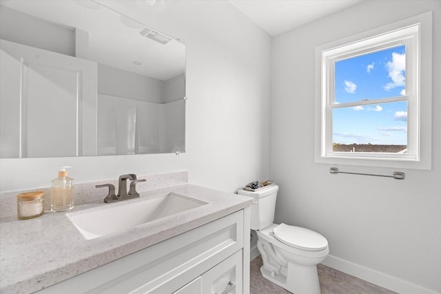 bathroom with toilet, vanity, baseboards, and a shower