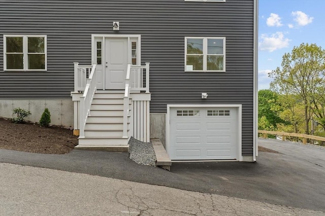 entrance to property featuring an attached garage and asphalt driveway
