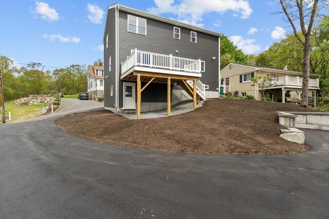 back of house with stairs, a deck, and driveway