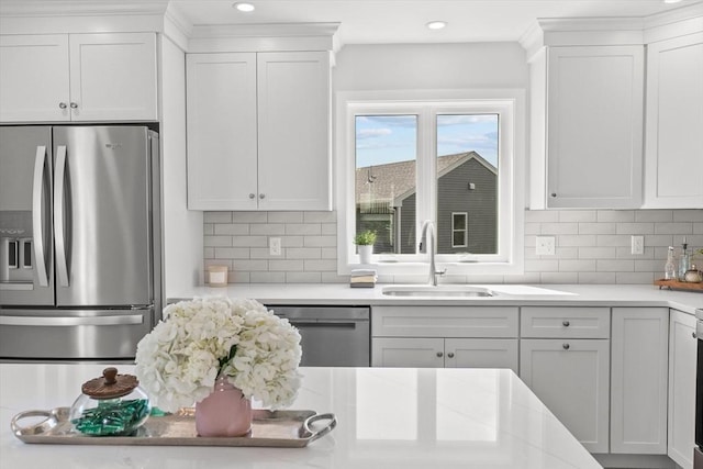 kitchen featuring stainless steel appliances, a sink, light countertops, white cabinetry, and recessed lighting