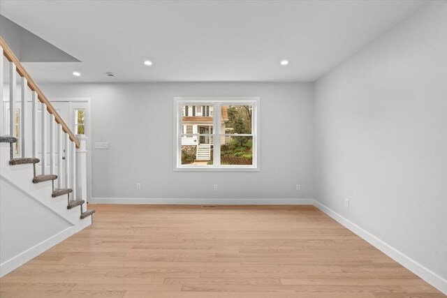 empty room featuring stairs, recessed lighting, baseboards, and light wood-style flooring