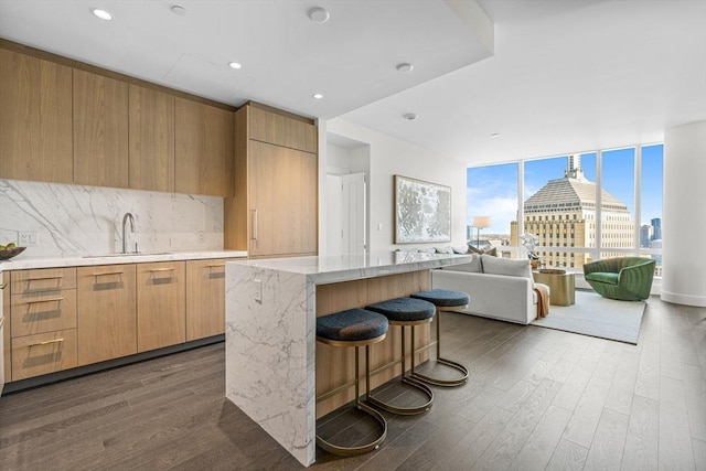 kitchen featuring sink, dark wood-type flooring, backsplash, a center island, and floor to ceiling windows