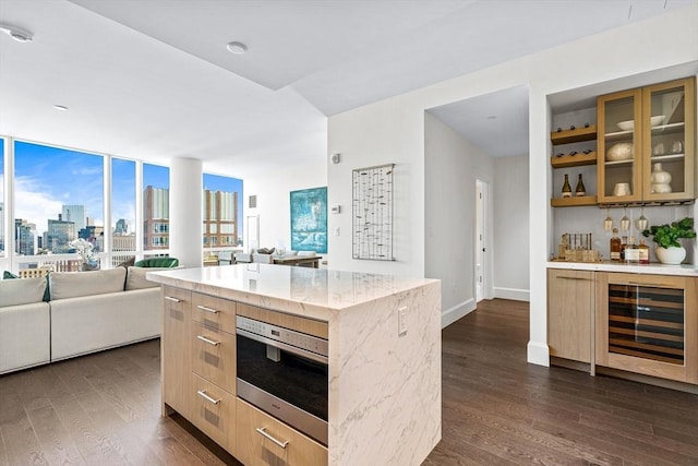 kitchen with wine cooler, dark hardwood / wood-style flooring, light stone counters, and a kitchen island