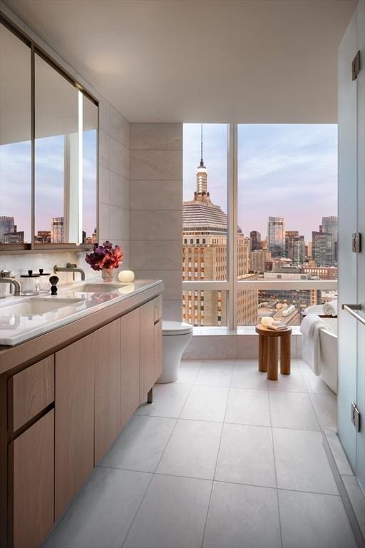 bathroom featuring tile patterned flooring, sink, tile walls, and toilet