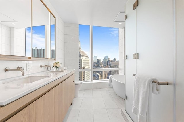 bathroom with vanity, a tub, tile patterned floors, and toilet