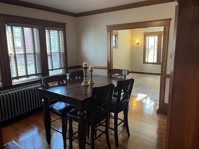 dining room with hardwood / wood-style flooring, radiator heating unit, and ornamental molding