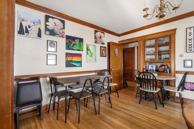 dining space with a chandelier, ornamental molding, and light hardwood / wood-style floors