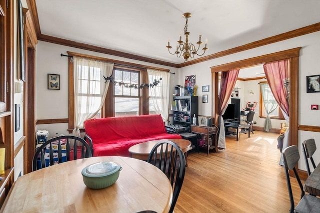 dining space featuring crown molding, light wood-type flooring, and a notable chandelier