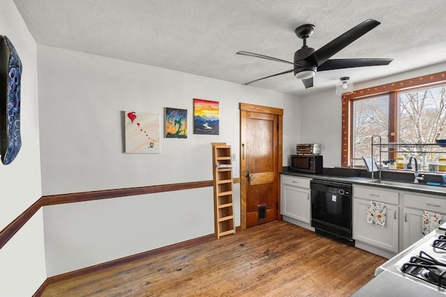 kitchen with white cabinets, black appliances, ceiling fan, sink, and hardwood / wood-style flooring