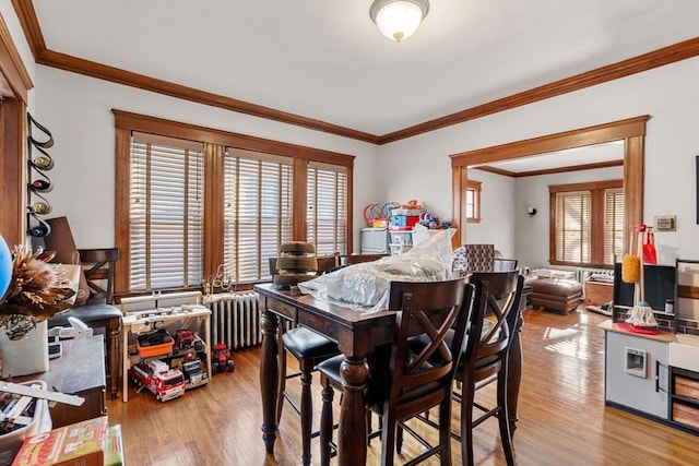 dining room featuring radiator, crown molding, and light wood-type flooring