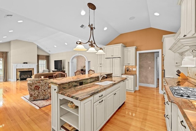 28 Ridgewood Xing Unit 28, Hingham, MA 02043 - kitchen with lofted ceiling, stainless steel gas stovetop, white cabinetry, light wood-style floors, and a glass covered fireplace