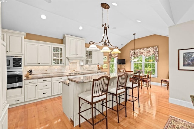 28 Ridgewood Xing Unit 28, Hingham, MA 02043 - kitchen featuring stainless steel appliances, backsplash, a breakfast bar area, light wood-style flooring, and vaulted ceiling