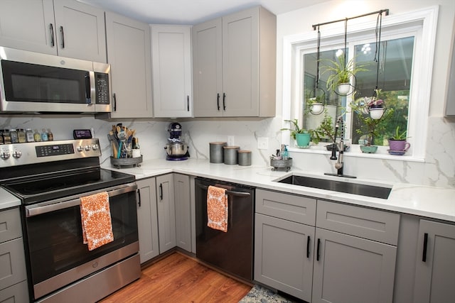 kitchen featuring tasteful backsplash, light hardwood / wood-style floors, appliances with stainless steel finishes, and gray cabinetry