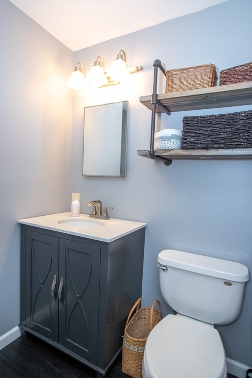 bathroom with hardwood / wood-style floors, vanity, and toilet