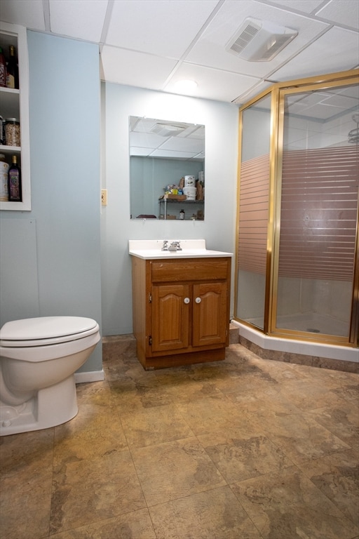 bathroom featuring vanity, a paneled ceiling, toilet, and an enclosed shower