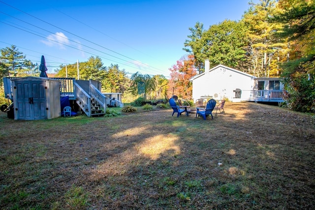 view of yard featuring a fire pit, a storage unit, and a deck