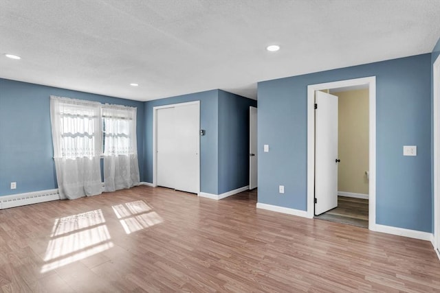 49 Wimbleton Dr, Longmeadow, MA 01106 - unfurnished living room featuring wood finished floors, a textured ceiling, baseboards, recessed lighting, and a baseboard radiator