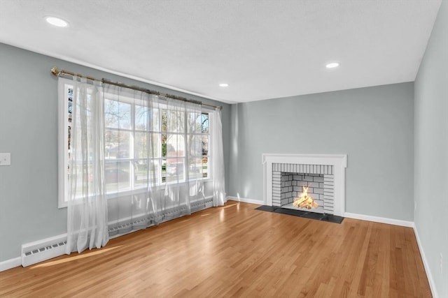 49 Wimbleton Dr, Longmeadow, MA 01106 - unfurnished living room with baseboards, wood finished floors, a brick fireplace, recessed lighting, and a baseboard radiator