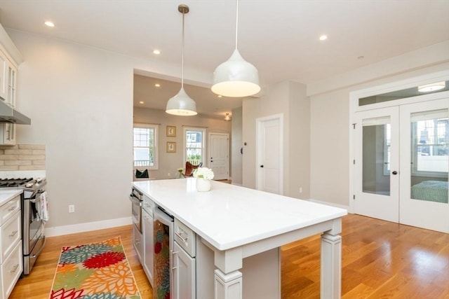 kitchen with light hardwood / wood-style floors, stainless steel appliances, pendant lighting, and a center island