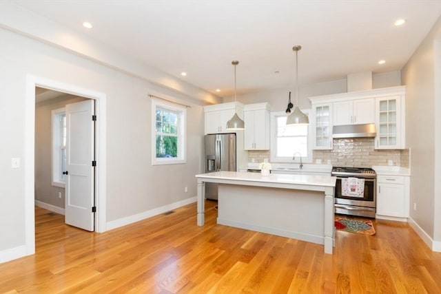 kitchen with white cabinets, pendant lighting, stainless steel appliances, and a kitchen island