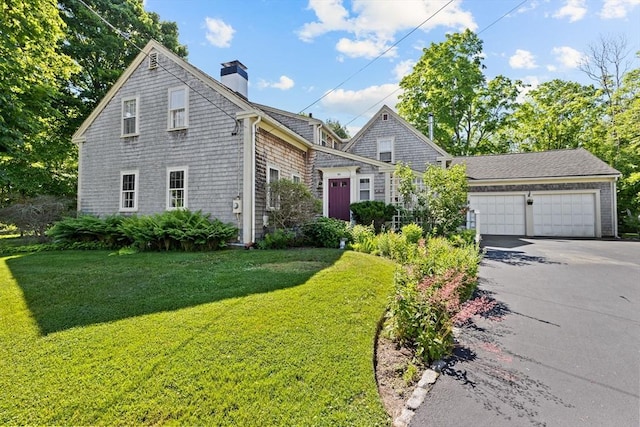 shingle-style home with asphalt driveway, a front yard, a chimney, and a garage