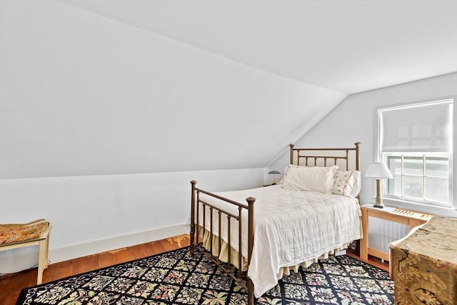bedroom with vaulted ceiling, wood finished floors, and radiator heating unit