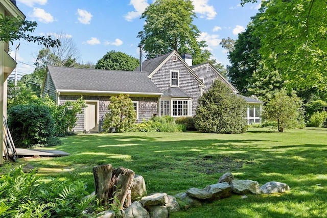 view of front of home featuring a front yard, a chimney, and roof with shingles
