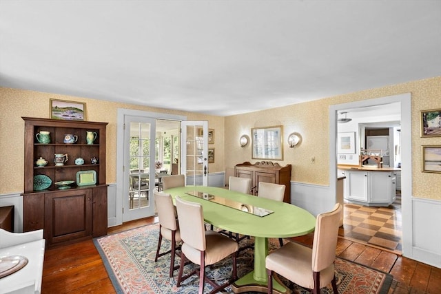dining space featuring hardwood / wood-style flooring, wallpapered walls, and wainscoting
